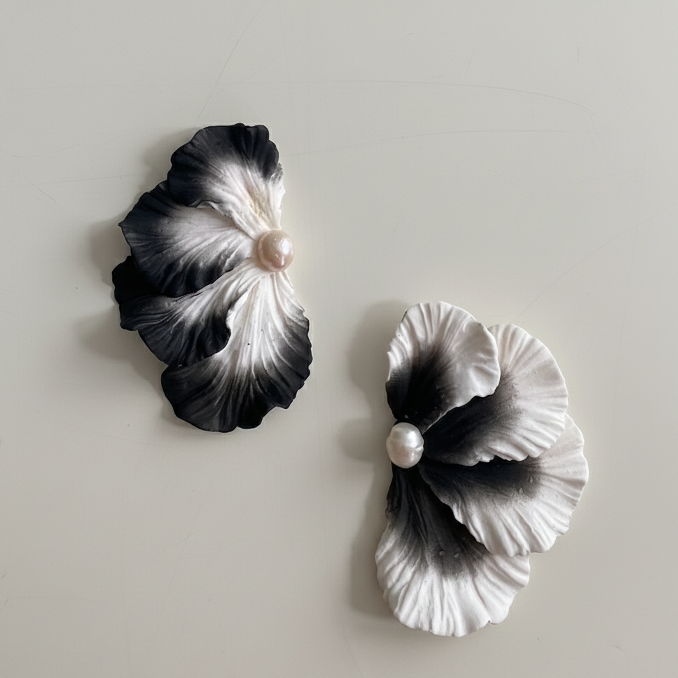 Black and white floral earrings with pearls on a light gray background