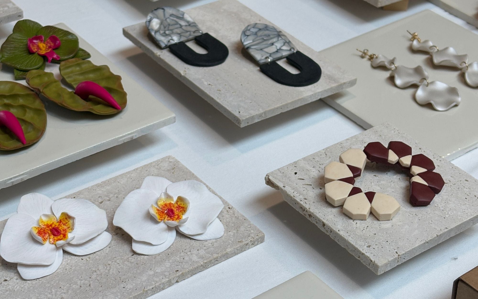 Collection of KENZA KLAY earrings on concrete stands with a white background